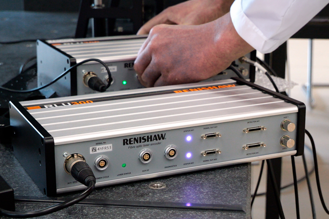 Two RLU300 laser units for interferometric laser encoders in front of each other with two hands connecting the back unit