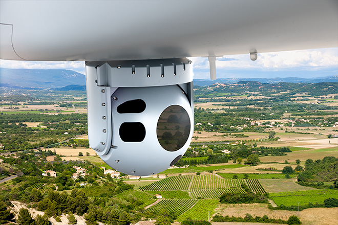 Spherical camera or sensor pod mounted beneath an aircraft, with multiple circular lenses and openings.