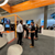 People networking at a modern exhibition booth with orange framing and digital displays at Formnext 2024.