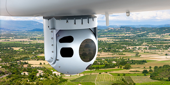 Spherical camera or sensor pod mounted beneath an aircraft, with multiple circular lenses and openings.