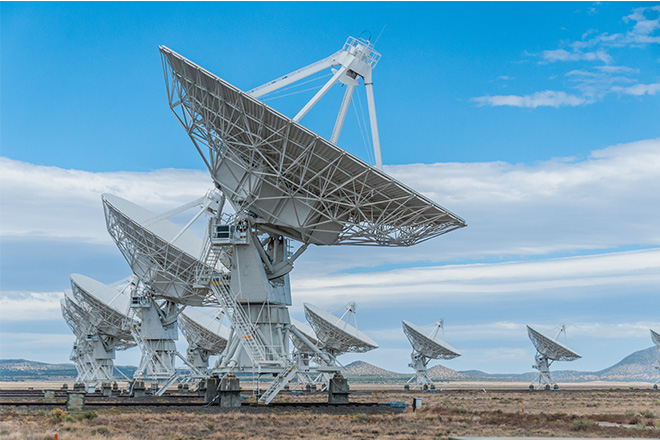 Large white satellite dishes mounted on metal structures, angled toward the sky.