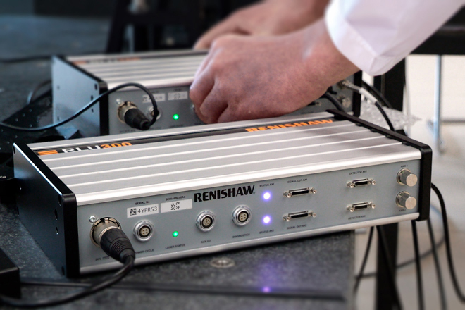 Two RLU300 laser units for interferometric laser encoders in front of each other with two hands connecting the back unit